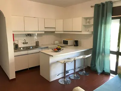 a kitchen with white cabinets and a sink and stools at BREEZY NEST by ITHOUSE in Albufeira
