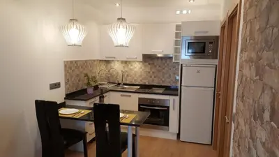a kitchen with white appliances and a table with chairs at Apartamento Cardoso II. A 5 minuto a pé da praia do Peneco in Albufeira