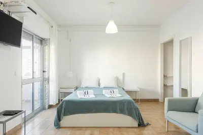a white bedroom with a bed and a chair at Sea Studio in Quarteira
