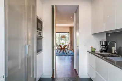 a kitchen with white cabinets and a door leading into a dining room at Vilamoura Charming Apartment by Intiholidays in Vilamoura