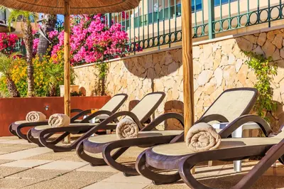 a row of chaise lounges with an umbrella at Lakeside Country Club - Apartamentos Turísticos in Quinta do Lago