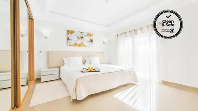 a white bedroom with a white bed and a mirror at Lakeside Country Club - Apartamentos Turísticos in Quinta do Lago