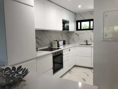 a white kitchen with white cabinets and appliances at Victory Village 1B Quinta do Lago in Quinta do Lago