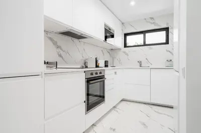 a white kitchen with white marble walls and counters at Victory Village 1B Quinta do Lago in Quinta do Lago