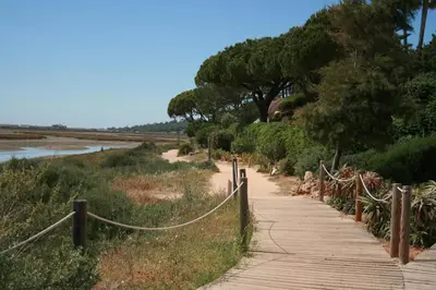 a wooden path with a fence next to a river at Victory Village 1B Quinta do Lago in Quinta do Lago
