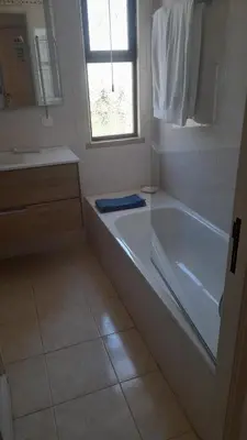 a white bathroom with a tub and a window at A Apartmento Solar dos Pinheiros in Vilamoura