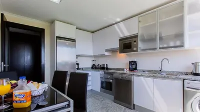a kitchen with white cabinets and a glass table at Monte Laguna Duplex - Greice Homes in Vilamoura