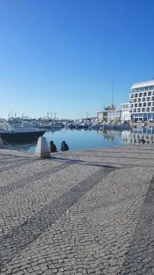 two people sitting next to a body of water at Residencial Condado in Faro