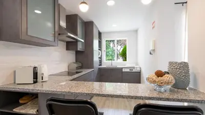 a kitchen with a counter with chairs and a sink at Vale do Lobo - Casa de La Rosa in Vale do Lobo