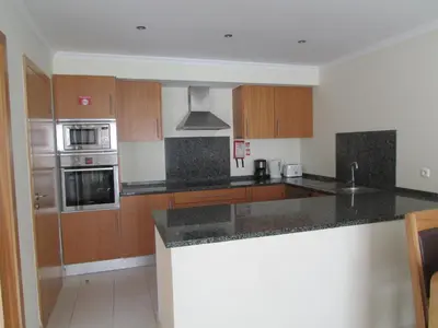a kitchen with granite counter tops and wooden cabinets at Vista das Ondas in Albufeira