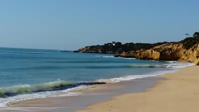 a beach with the ocean and rocks in the background at Vista das Ondas in Albufeira
