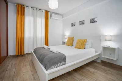a white bedroom with a white bed and yellow curtains at #002 Donalds Flat by Home Holidays in Albufeira