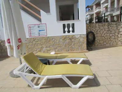 two lounge chairs sitting on a patio in front of a building at Apartamentos Cabrita in Albufeira
