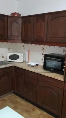 a kitchen with wooden cabinets and a microwave on a counter at Apartamento Sao Jose in Albufeira