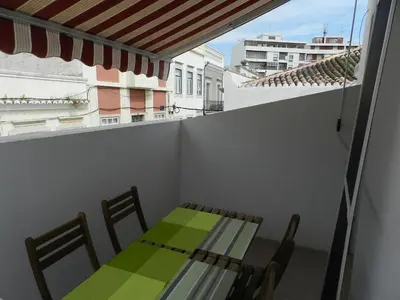 a table and chairs on a balcony with a green table and chairs at Casa Da Baixa in Faro