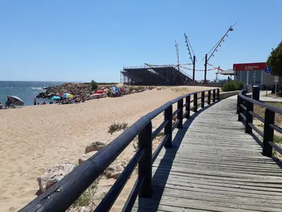 a wooden boardwalk leading to a beach with people on it at COLINA FÉRIAS- Garagem & WIFI in Quarteira