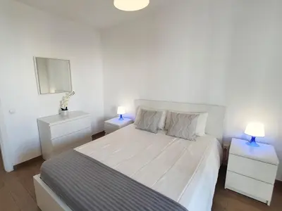 a white bedroom with a bed with two night stands at Pontemira 5 Esplêndido in Quarteira