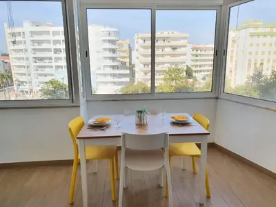 a dining room with a table and chairs and windows at Pontemira 5 Esplêndido in Quarteira