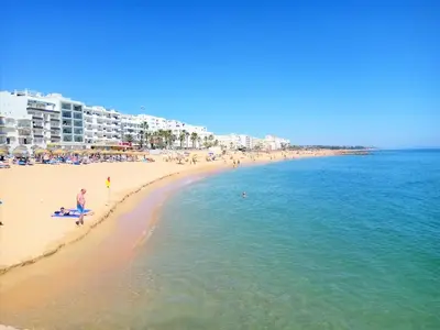 a beach with a lot of people in the water at Pontemira 5 Esplêndido in Quarteira