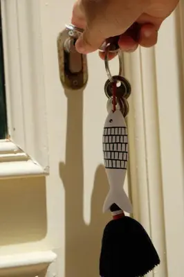 a persons hand holding a key chain with a black and white object at Yellow House - Checkinhome in Boliqueime