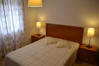 a bedroom with a large bed with two lamps at Apartamentos Cabrita in Olhos de Água