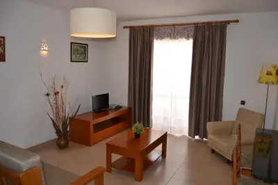 a living room with a couch and a table and a tv at Apartamentos Cabrita in Olhos de Água