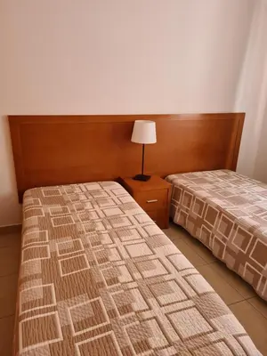 a bedroom with two beds and a lamp on a night stand at Apartamentos Cabrita in Olhos de Água