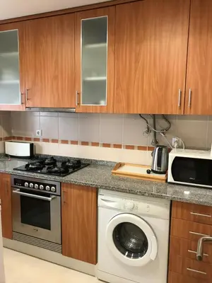 a kitchen with a refrigerator and a sink and a window at AP Roberand in Albufeira