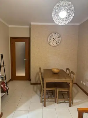 a dining room table with chairs and a clock on the wall at AP Roberand in Albufeira