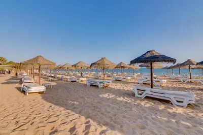 a beach with many chairs and umbrellas and the ocean at Villa V1 Vale do Lobo Beach in Vale do Lobo