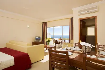 a bedroom with a bed and a dining room with a table at Silmar in Albufeira