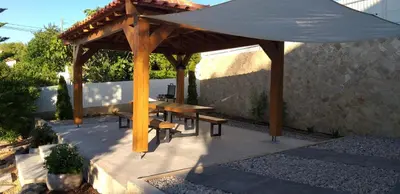 a wooden gazebo with a wooden table and benches at FIND Your Space Casa no Campo - Paderne - Albufeira - Piscina Privada - Aquecida a pedido in Paderne