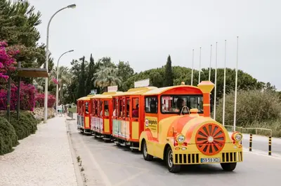a yellow and red train is driving down a street at Hello Chloé in Vilamoura