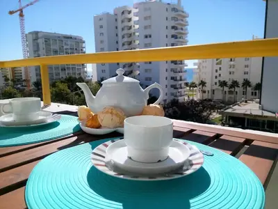 a table with cups and plates of tea on a balcony at Sol europa- Vista Mar, 150mt Praia, Wifi in Quarteira