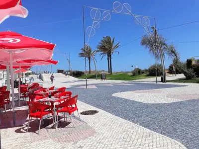 a group of red chairs and a table with a red umbrella at Sol europa- Vista Mar, 150mt Praia, Wifi in Quarteira