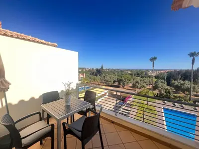 a balcony with a table and chairs and a pool at Apartamento Vista Golfe Mar Vilamoura in Vilamoura