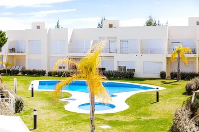 a palm tree in front of a building with a swimming pool at AL - Apartamento Terracos da Falesia in Vilamoura