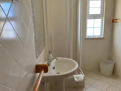 a white bathroom with a sink and a window at Guest House Alfarrobeiras in Albufeira