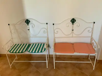 two white benches sitting next to each other at Guest House Alfarrobeiras in Albufeira