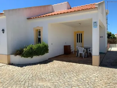 a white house with a patio and a table at Guest House Alfarrobeiras in Albufeira