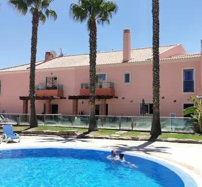 a couple swimming in a pool with palm trees at Albufeira Villa Santa Maria in Albufeira