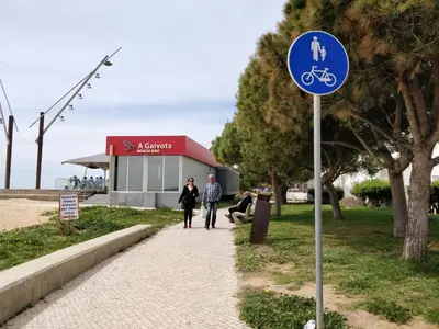 a blue sign on a sidewalk in front of a building at Oceanides Beachfront Apartments in Quarteira