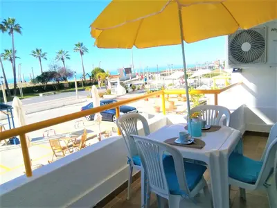 a table with a yellow umbrella and chairs on a balcony at T1 PraiaMar RC com Ar-Condicionado in Quarteira