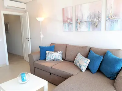 a living room with a brown couch and blue pillows at T1 PraiaMar RC com Ar-Condicionado in Quarteira