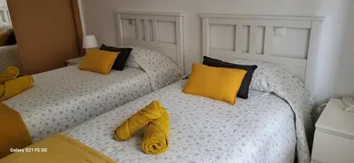 two beds in a room with yellow pillows at Apartamento T2 Encosta sao jose in Albufeira