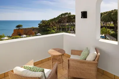a balcony with chairs and a table and a view of the ocean at Pine Cliffs Hotel, a Luxury Collection Resort, Algarve in Albufeira