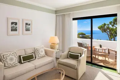 a living room with a couch and chairs and a balcony at Pine Cliffs Hotel, a Luxury Collection Resort, Algarve in Albufeira