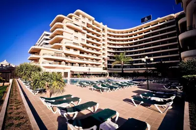 a large building with lounge chairs and a swimming pool at Vila Gale Marina in Vilamoura