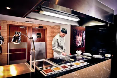 a chef standing in a kitchen preparing food at Vila Gale Ampalius in Vilamoura