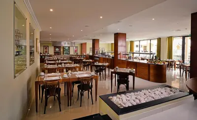 a dining room with tables and chairs and paintings on the walls at Vila Gale Atlantico in Albufeira